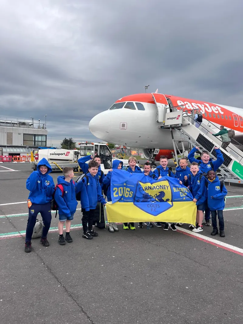 A squad at the airport beside the plane with their flag