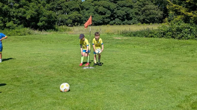 Two children at the flag on a foot golf green
