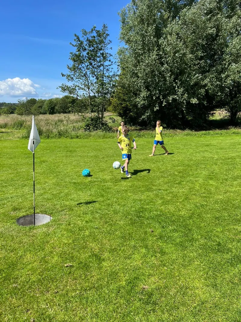 Children approaching a foot golf hole with the flag in the foreground