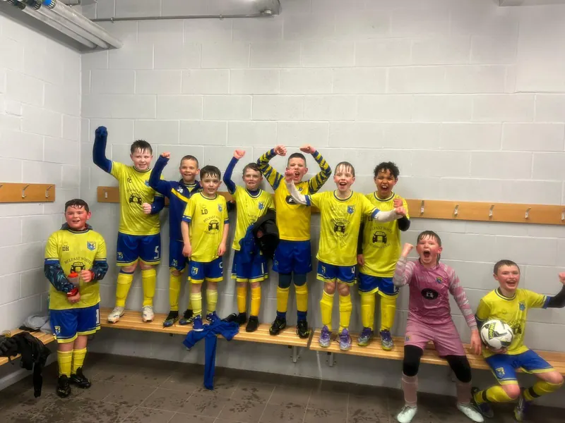 A squad cheering in a changing room after a match